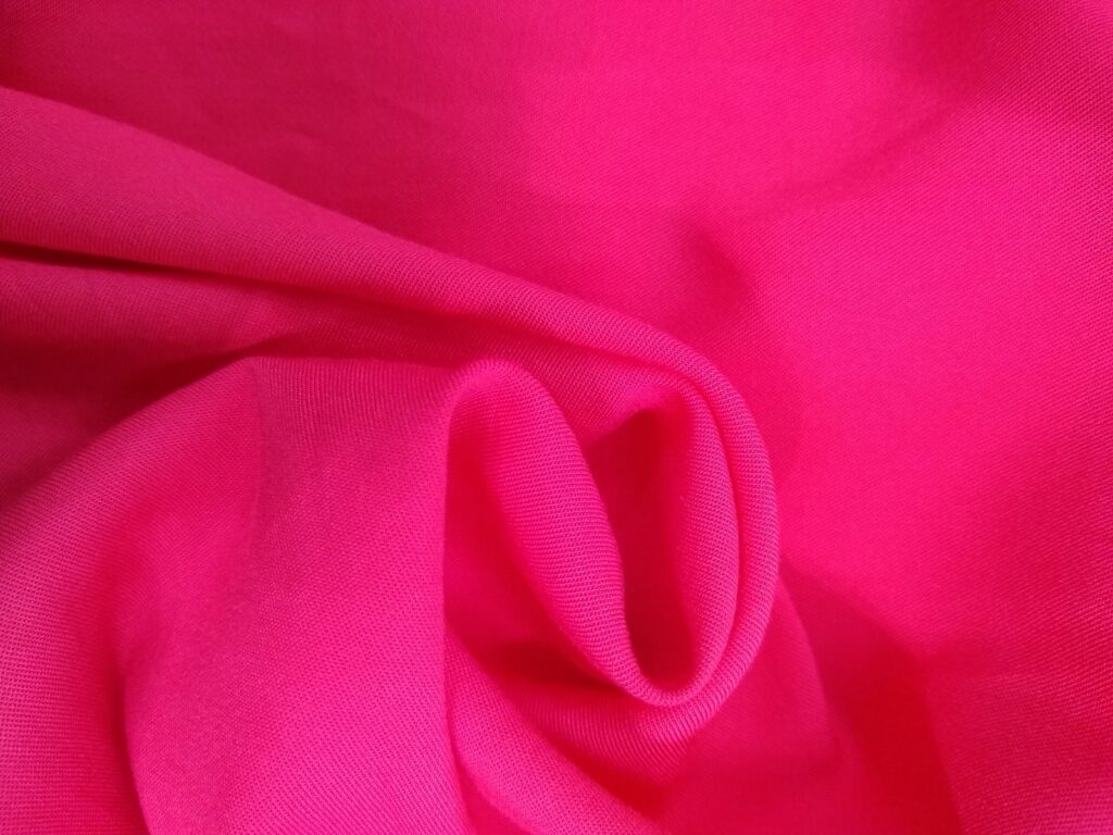 Pink rayon challis fabric arranged in soft folds to show the drape of one sample