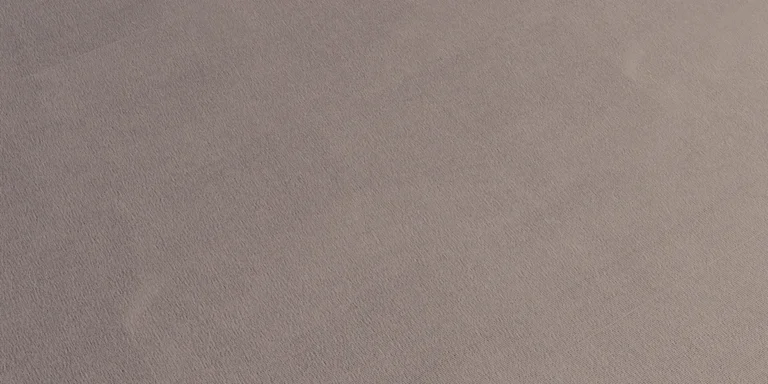 Close view of a neutral cotton jersey fabric surface showing fine knitted texture