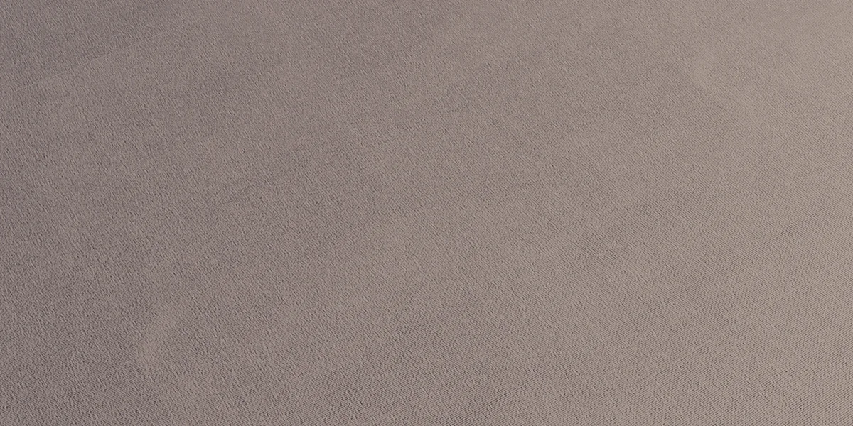 Close view of a neutral cotton jersey fabric surface showing fine knitted texture