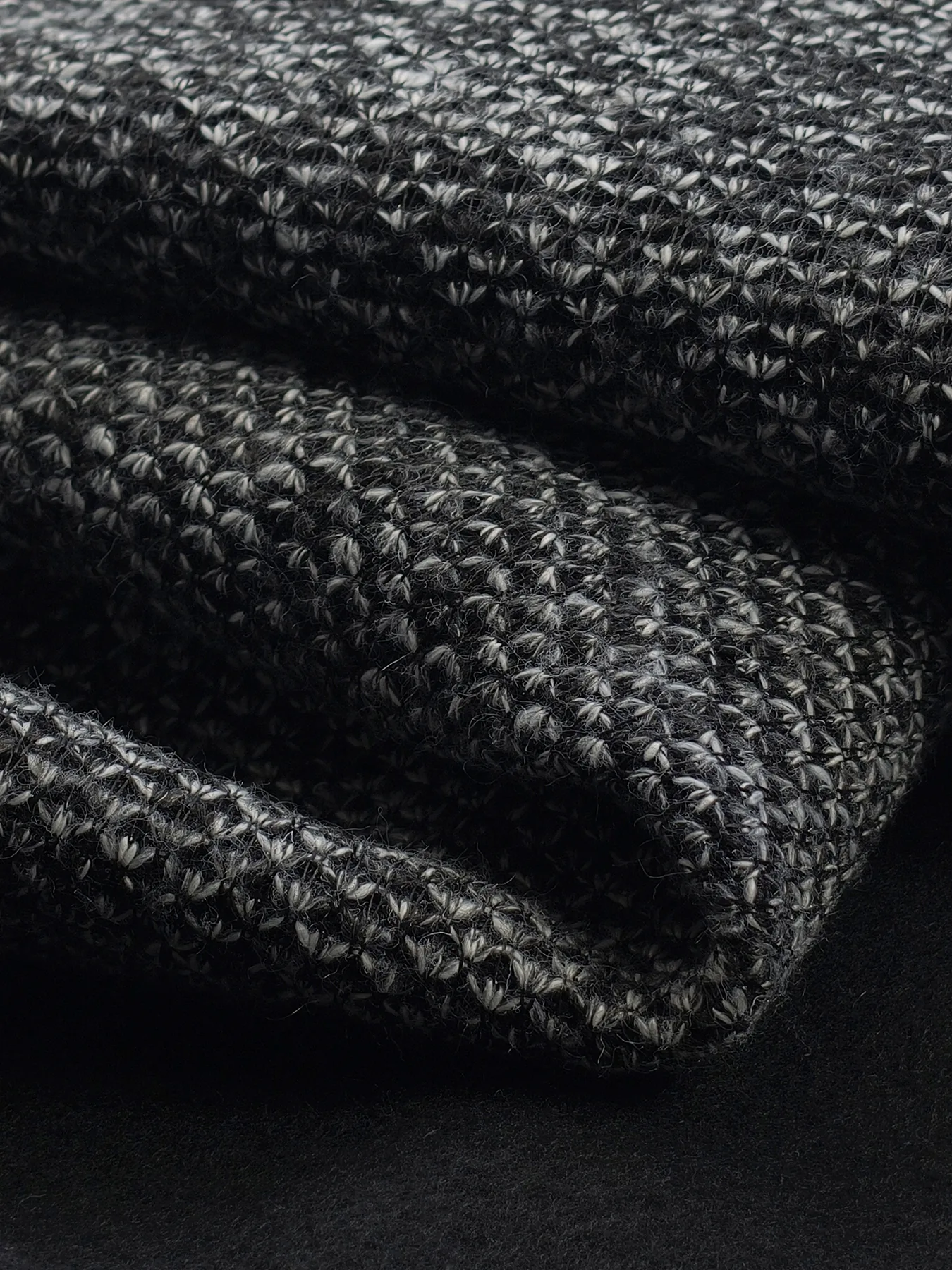 Folded WellDoneTex bonded-fabric sample showing a marled knit face and dark backing