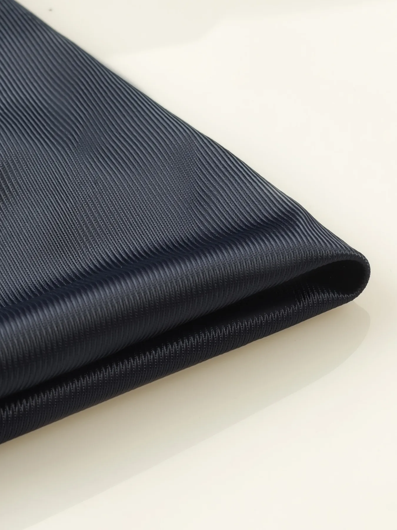 Folded WellDoneTex Tricot sample showing a fine ribbed surface